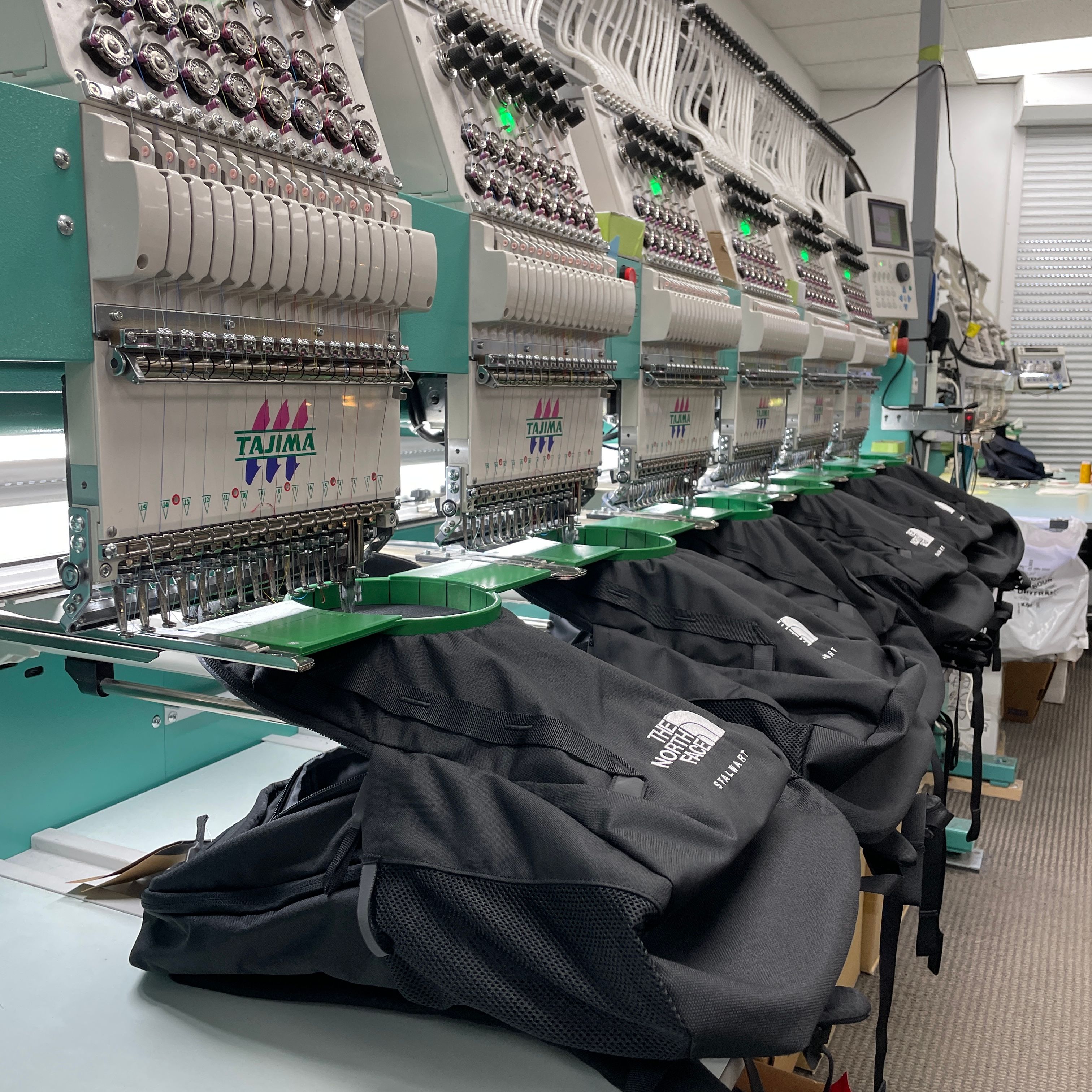 An image of our embroidery machines embroidering a design on North Face Backpacks