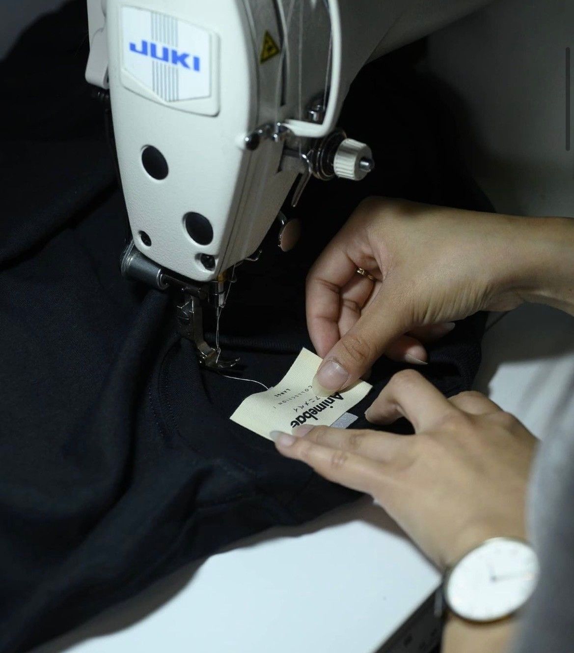 An image of our staff sewing on a custom neck tag.