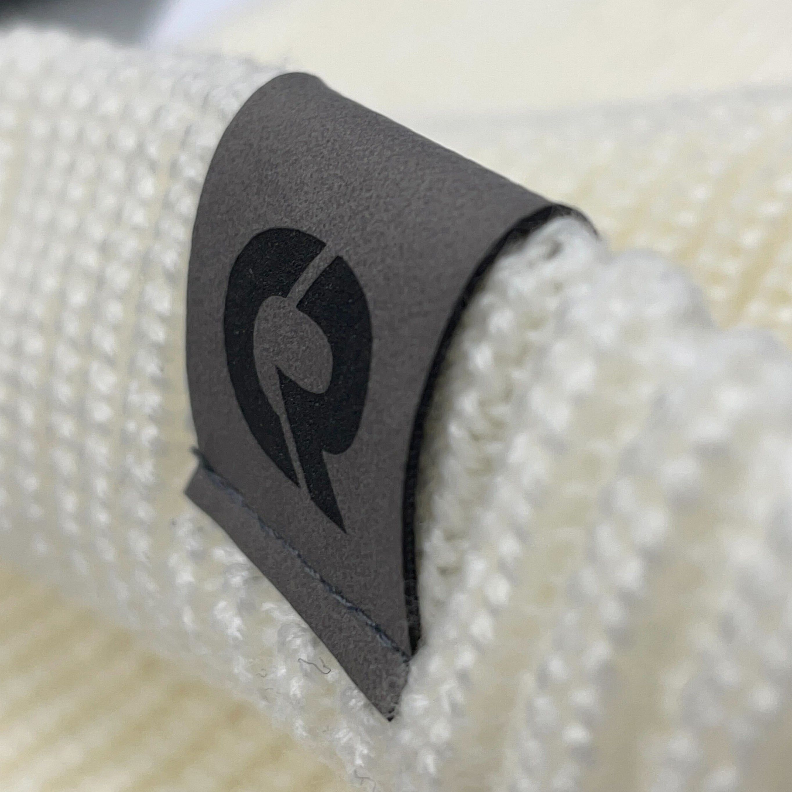 A close-up image of a custom leather label attached to a toque.