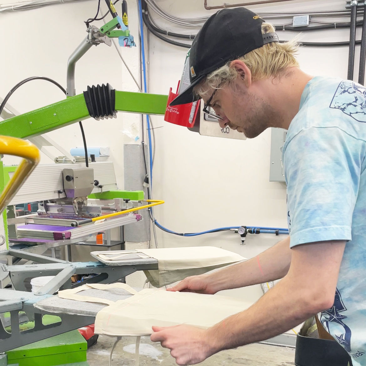 An image of our staff screen printing custom tote bags.