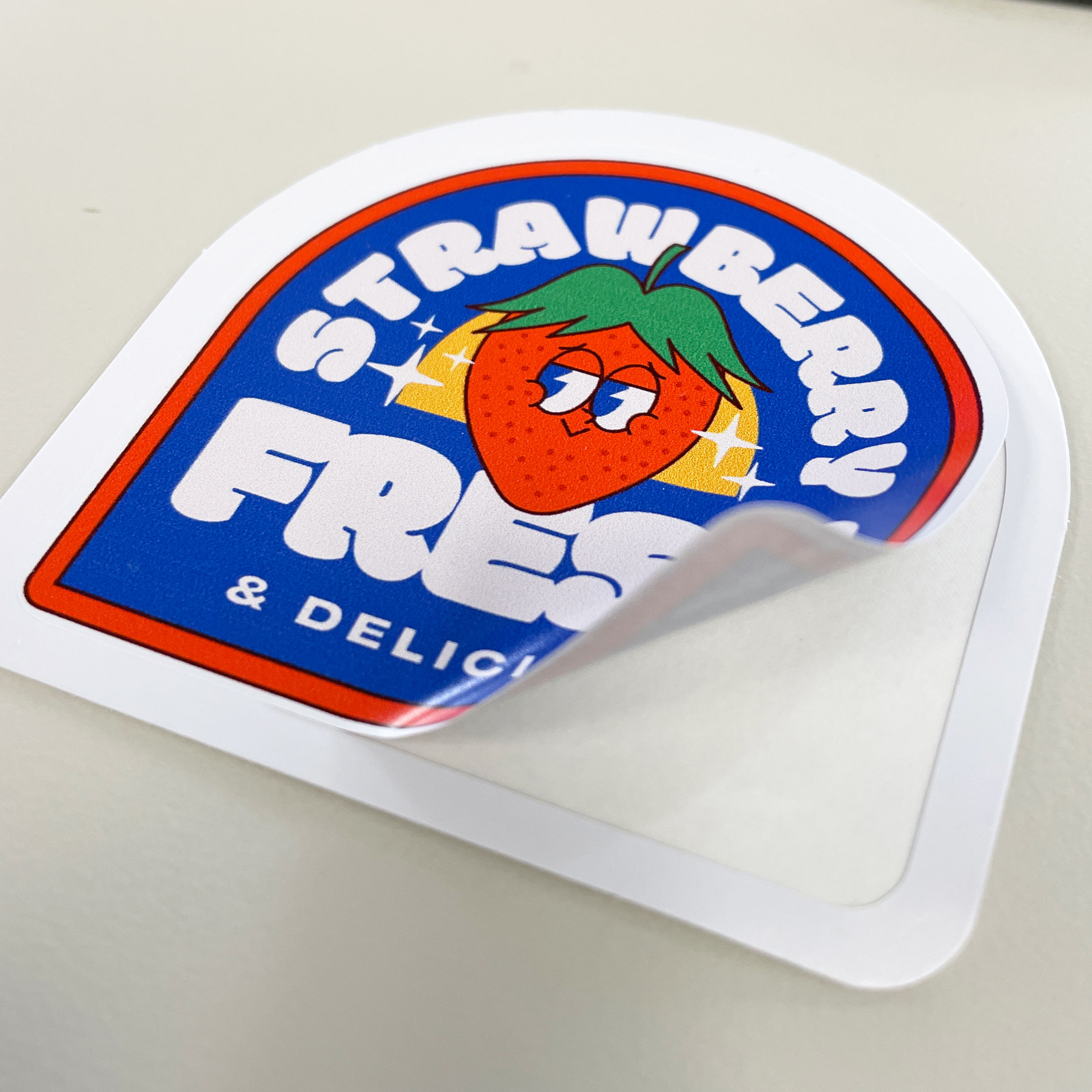 An image of a custom sticker we printed, with a colorful strawberry design.