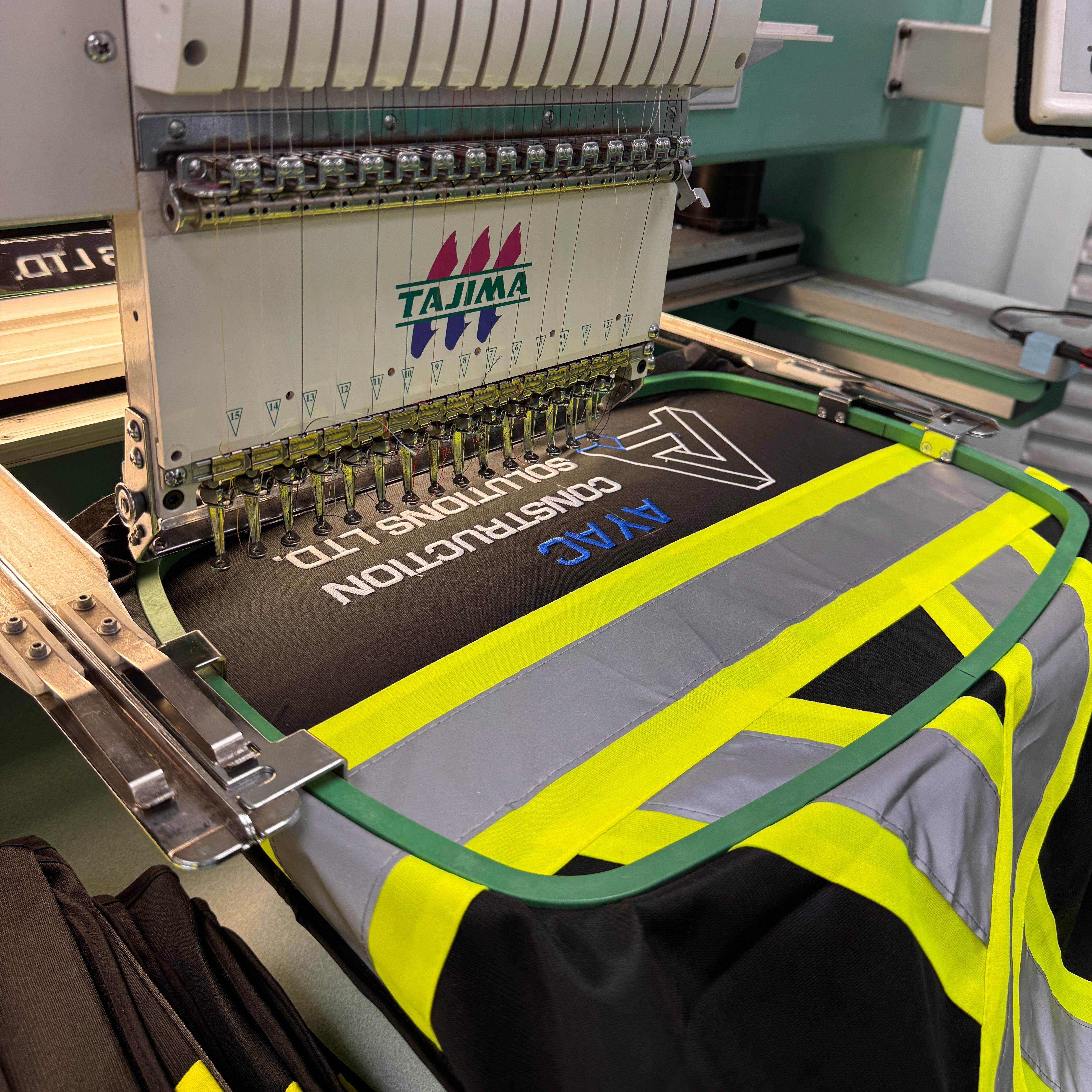 A company's logo being embroidered on the back of a safety garment.