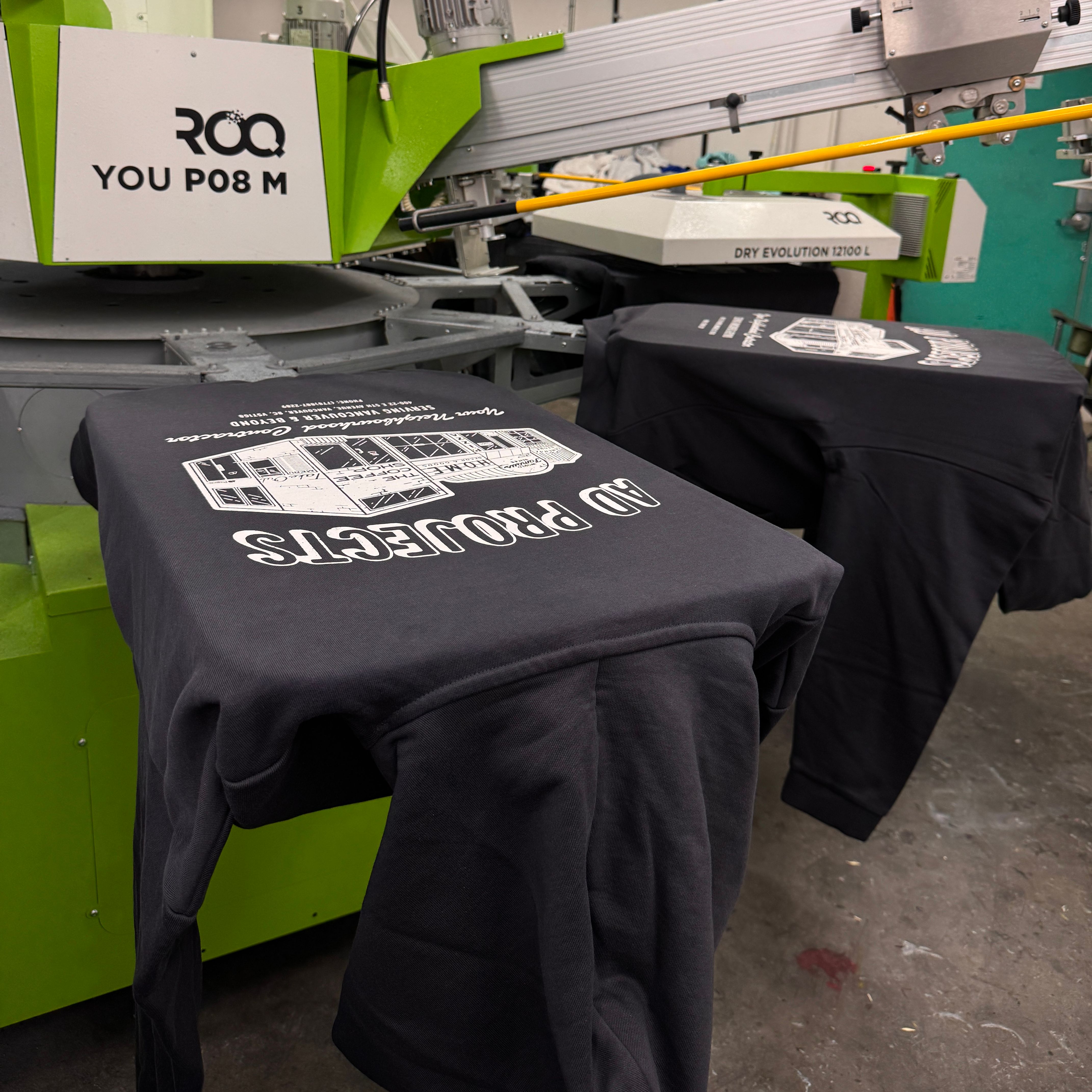 Hoodies are being screen printed on our ROQ automatic screen printing machine.