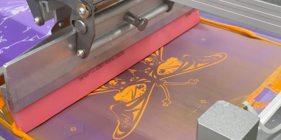 An image of one of our screen printers printing on our manual print machine.
