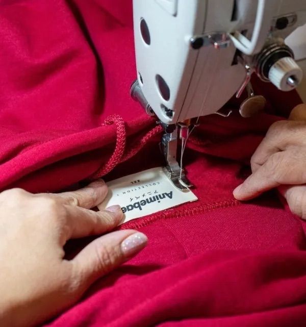 Our staff carefully sewing on custom tags on a hoodie