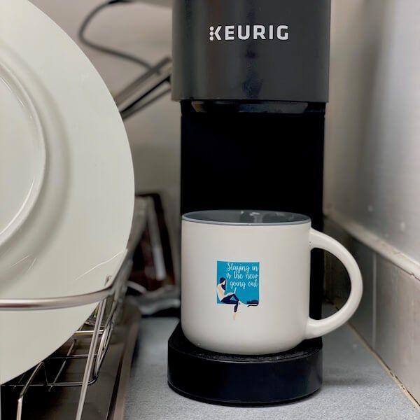 A custom ceramic mug being filled with a Keurig.