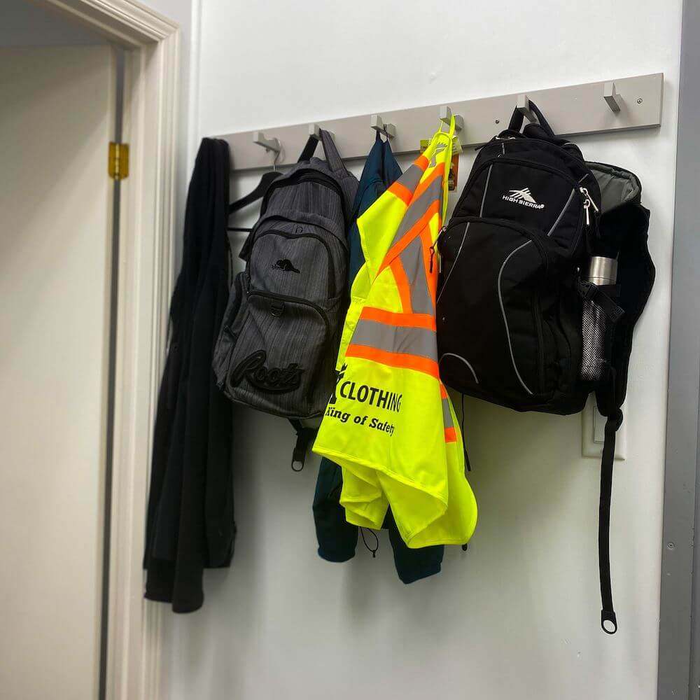 A bright yellow safety vest hung up on a clothing rack.